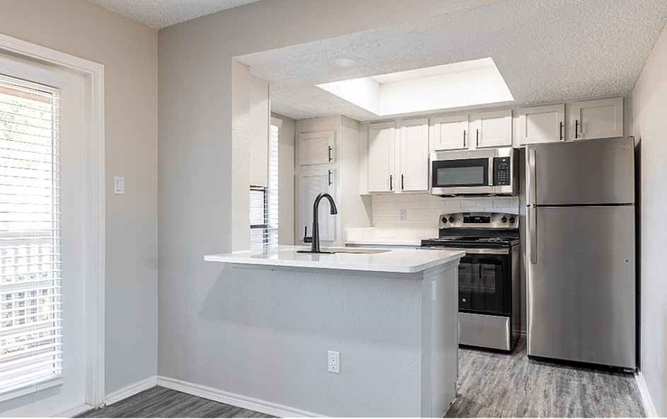Contemporary kitchen with modern stainless steel appliances and a bright, open layout.