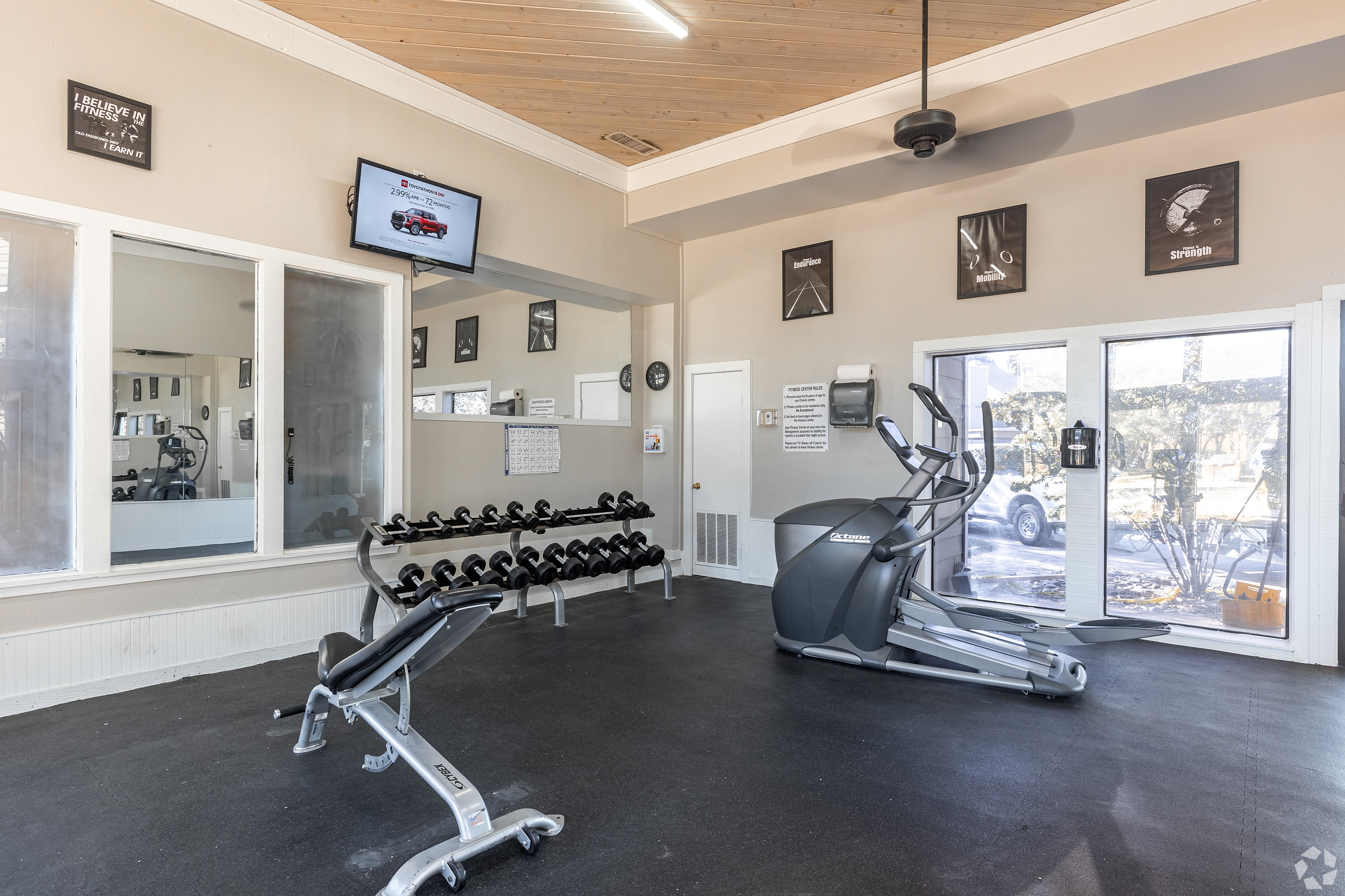 Modern gym with elliptical machine, free weights, and motivational decor.