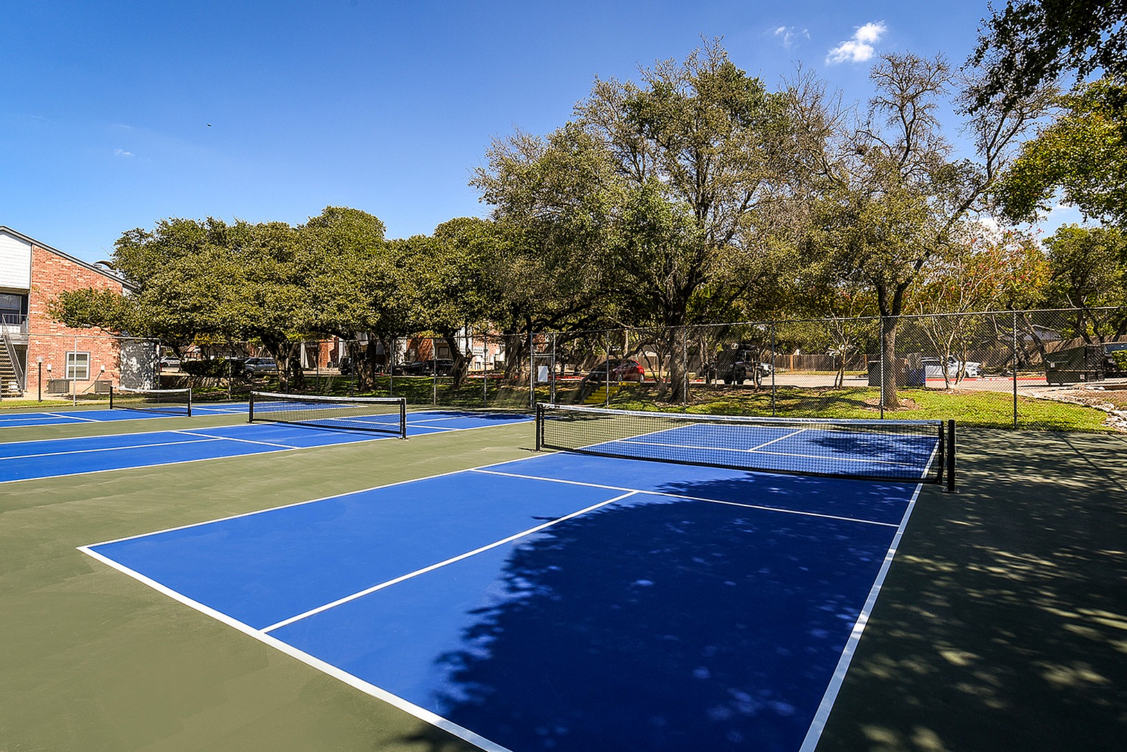Inviting outdoor tennis courts set amidst lush green surroundings, perfect for recreation and relaxation.