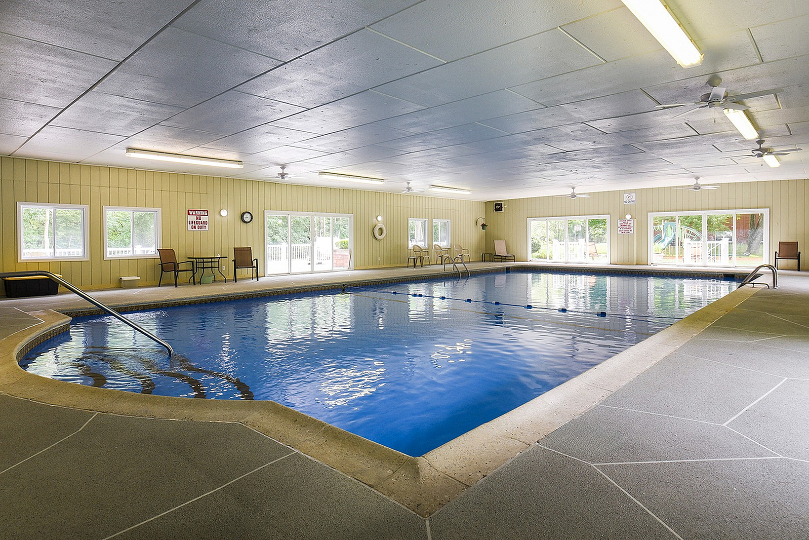 Luxurious indoor swimming pool with natural lighting, elegant design, and ample seating.