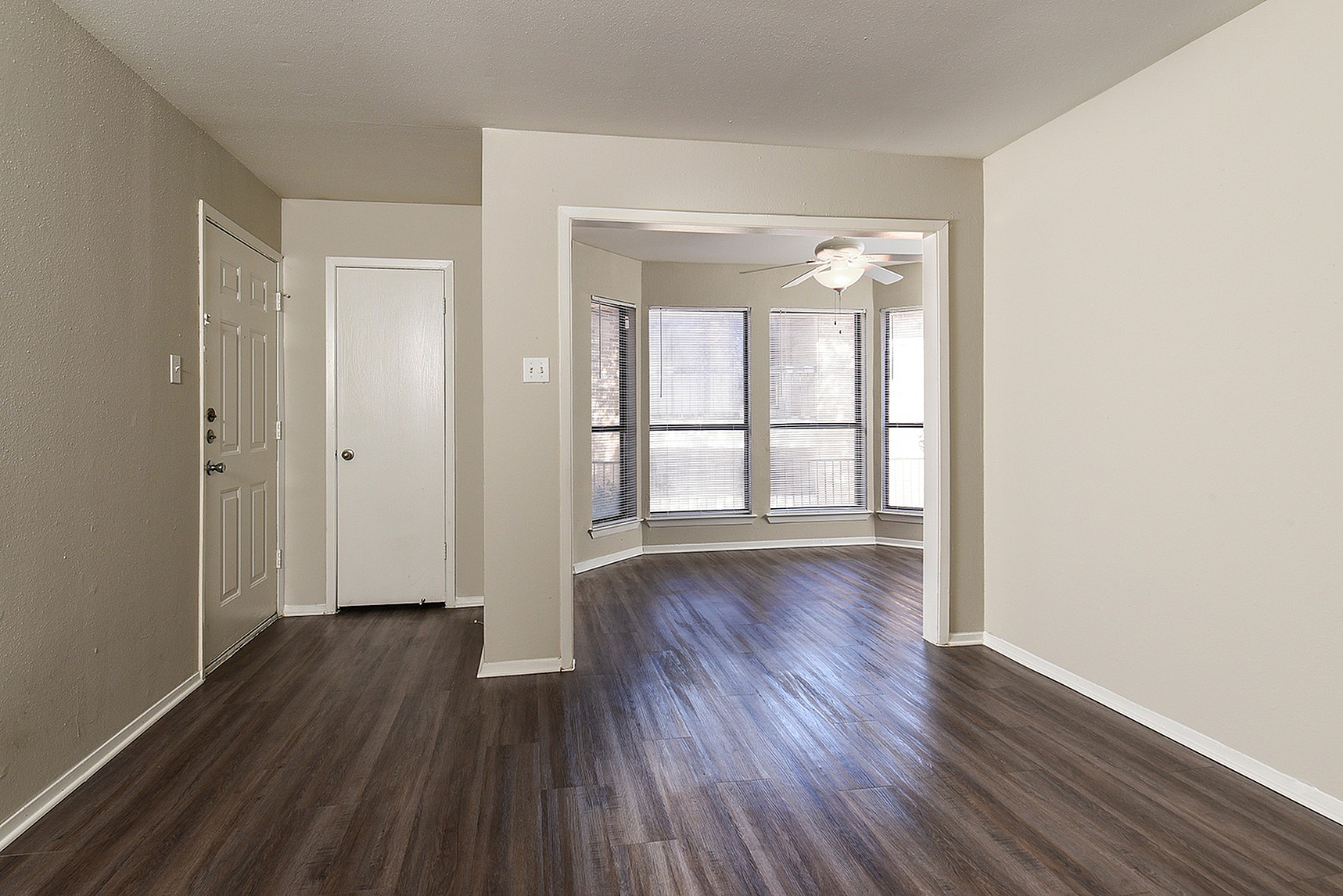 Bright living space with elegant wood flooring and large bay windows, perfect for natural light and modern design.