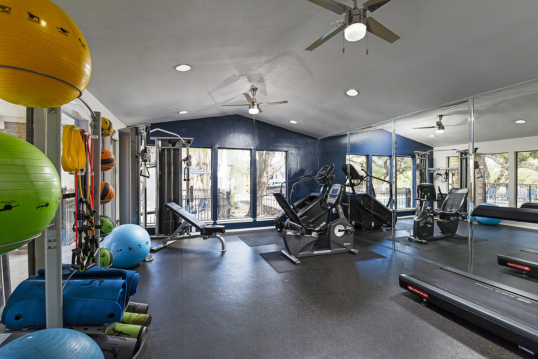 Modern fitness center with state-of-the-art equipment, vibrant exercise balls, and mirrored walls reflecting natural light.