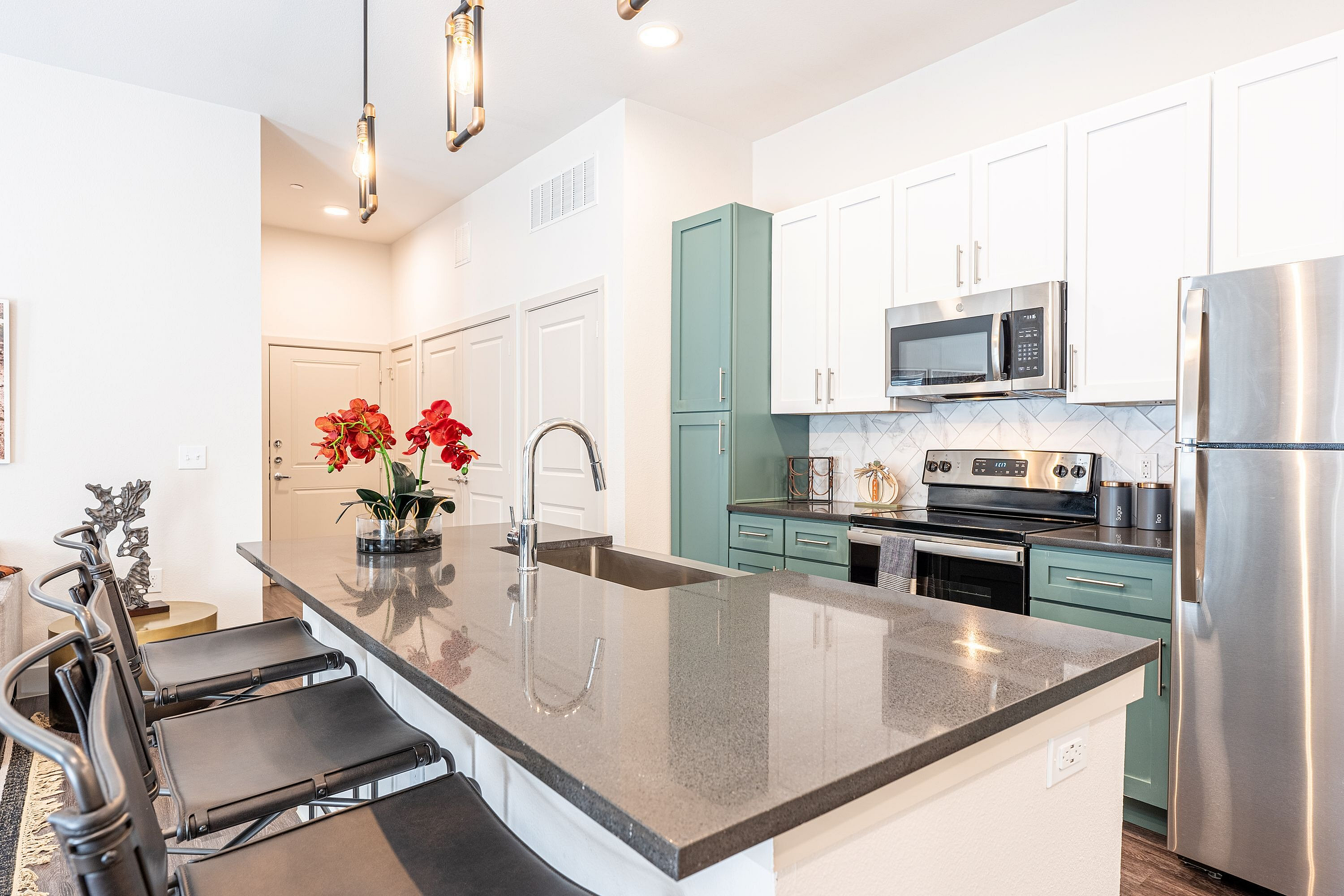 Modern kitchen design featuring sleek countertops, stainless steel appliances, and stylish pendant lighting, perfect for culinary enthusiasts.