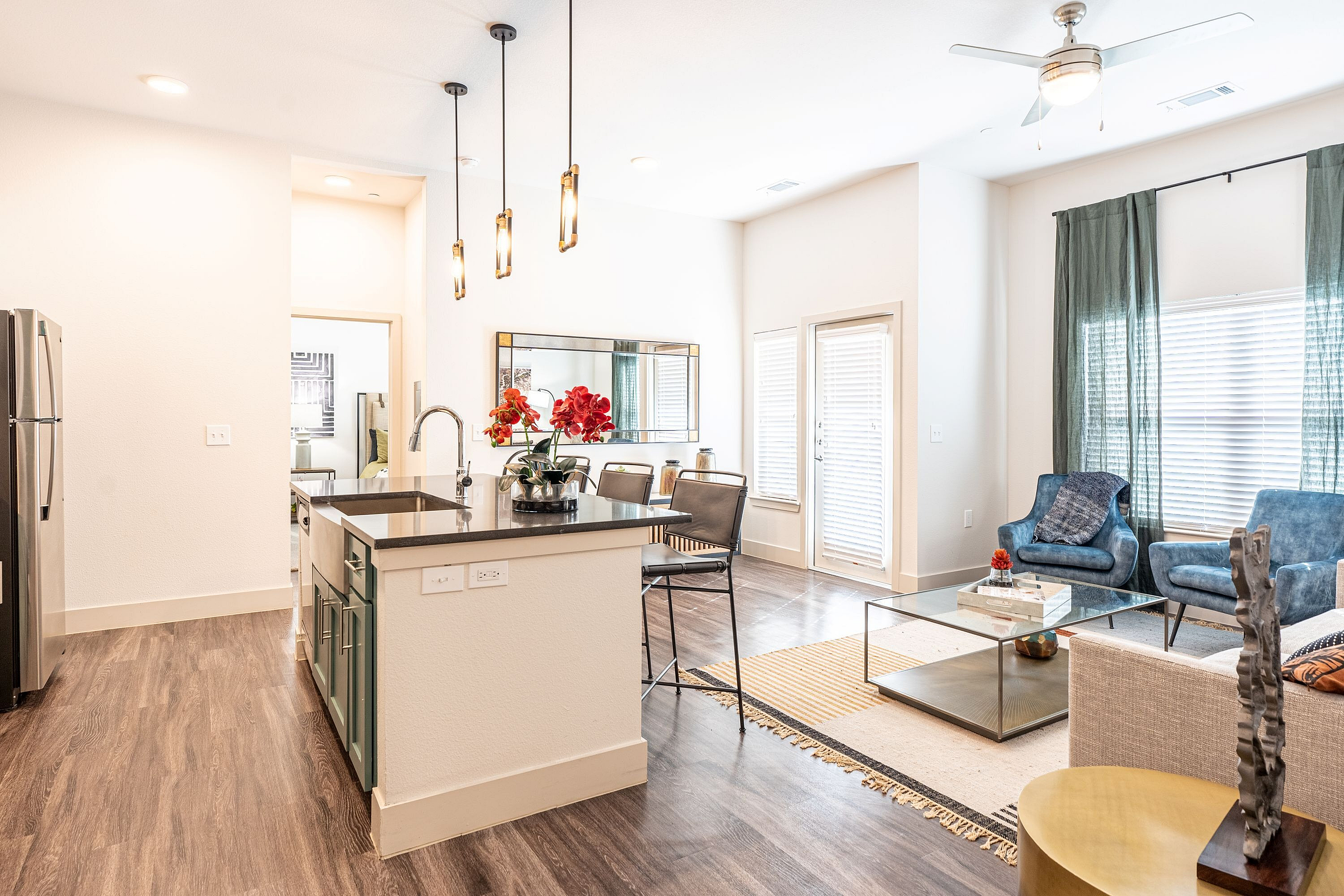 Bright and modern open-concept living space with a stylish kitchen island, elegant pendant lighting, and a cozy seating area with natural light.