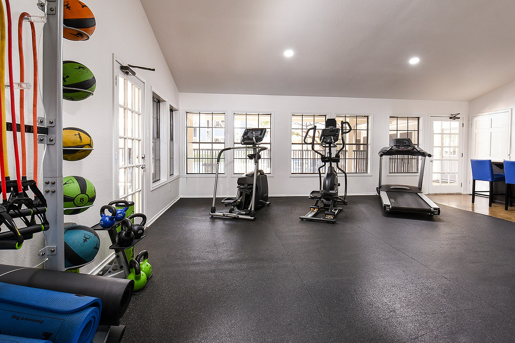 Bright and modern fitness center featuring state-of-the-art cardio machines, vibrant exercise equipment, and ample natural light.
