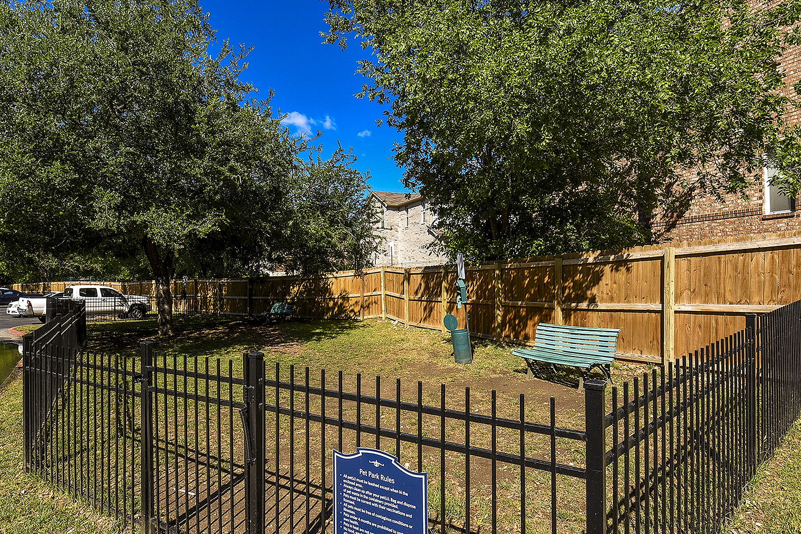 Charming private dog park with lush trees, a cozy bench, and secure fencing, perfect for pet-friendly living.