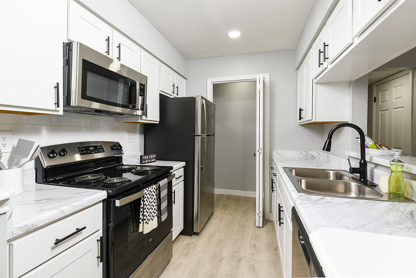 Sleek modern kitchen with stainless steel appliances, elegant white cabinetry, and polished marble countertops.