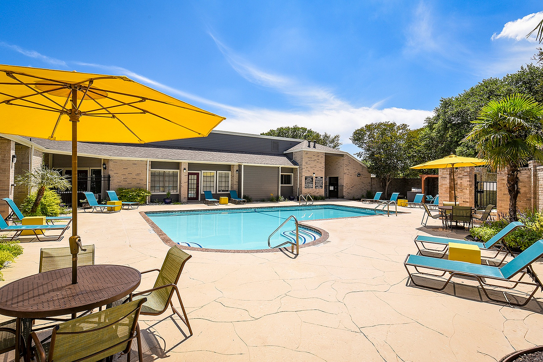 Inviting outdoor swimming pool area with sun loungers and bright yellow umbrellas, perfect for relaxing on a sunny day.