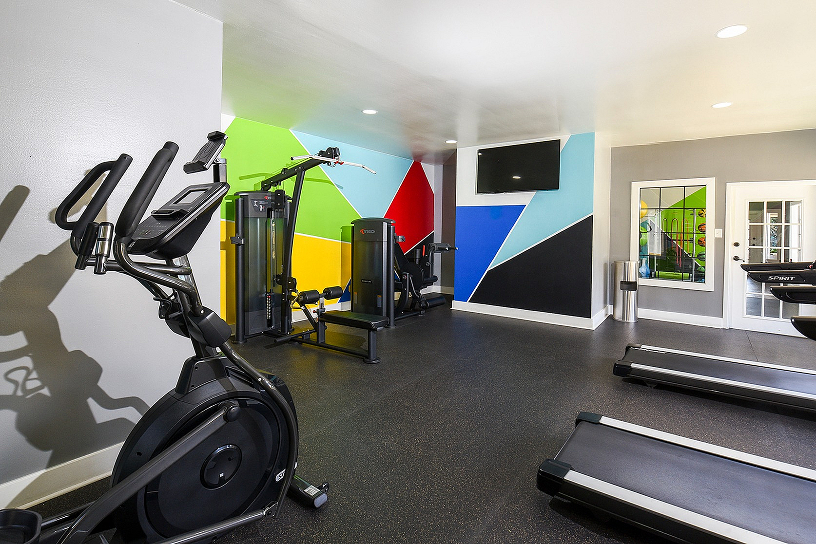 Vibrant fitness center with state-of-the-art equipment and colorful geometric wall art.