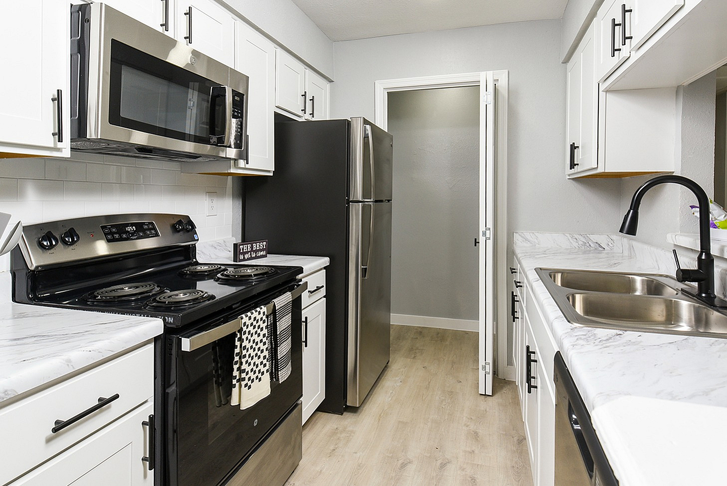 Contemporary kitchen with sleek stainless steel appliances, elegant marble countertops, and stylish white cabinetry.