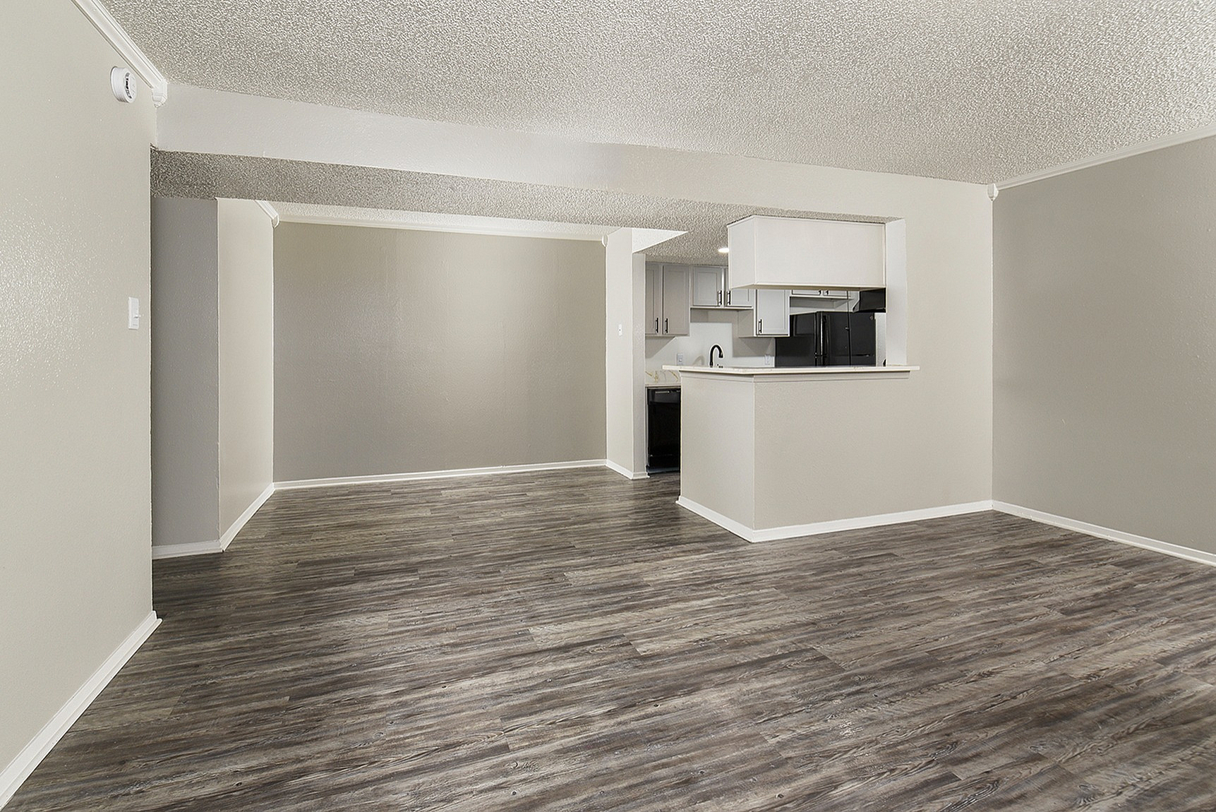 Spacious open-plan living room with modern laminate flooring and a sleek kitchen with stylish cabinetry.