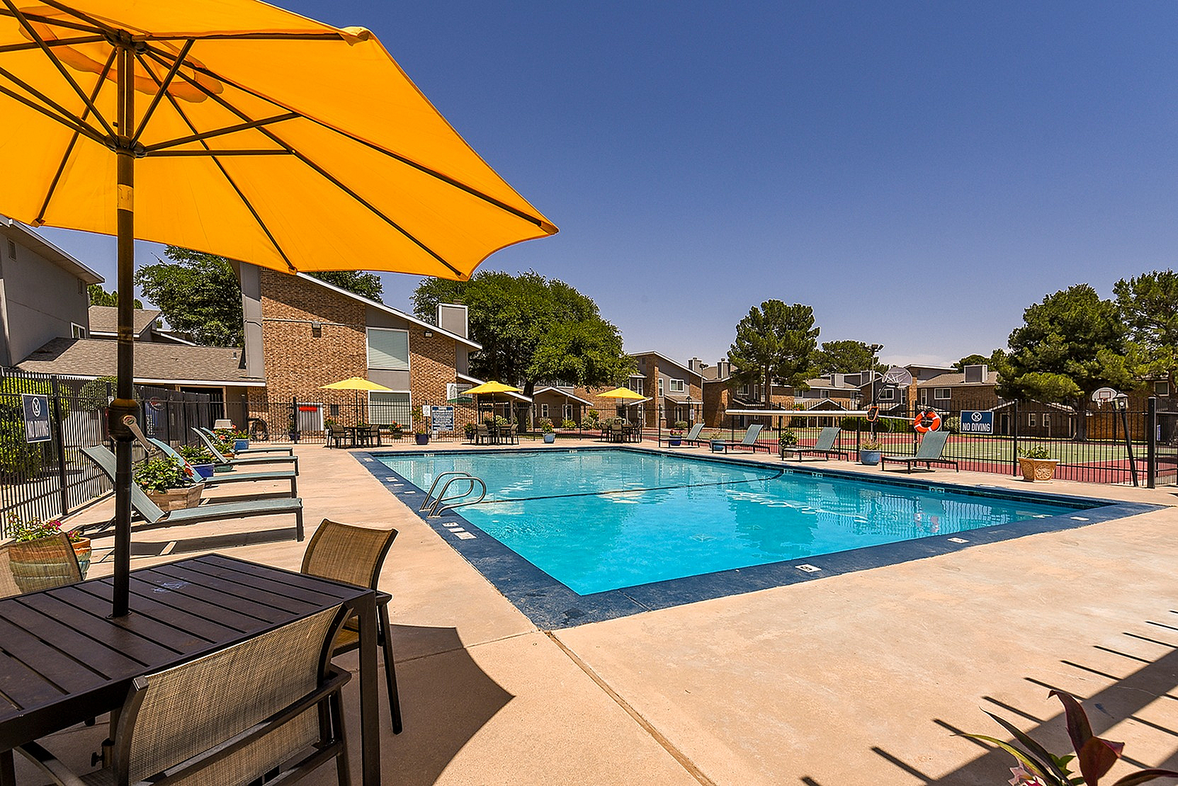 Inviting outdoor pool area with vibrant yellow umbrellas, surrounded by comfortable lounge chairs and lush greenery.