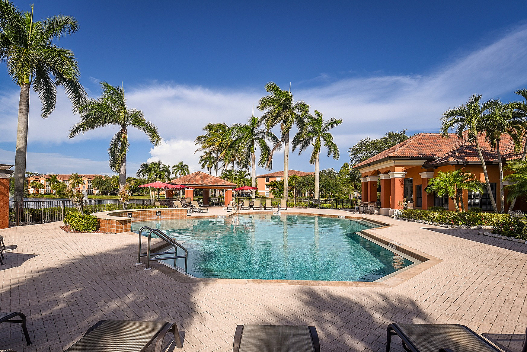 Inviting resort-style pool with scenic palm trees and elegant clubhouse backdrop, ideal for luxurious relaxation.