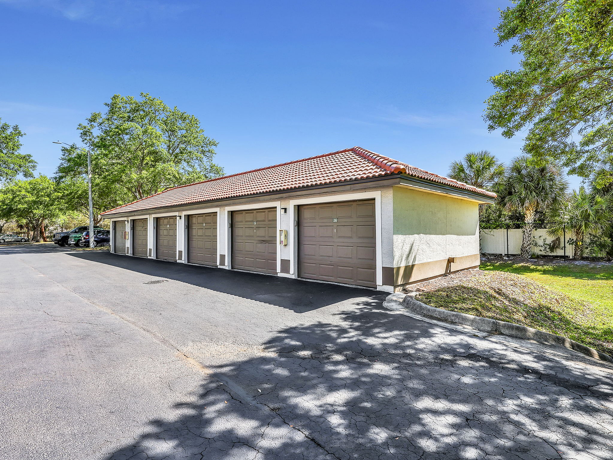 Charming garage units with classic red-tiled roof surrounded by lush greenery, offering secure and convenient parking.