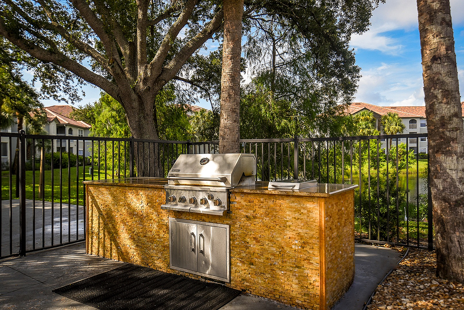 Inviting outdoor barbecue area with a stylish grill set against lush greenery and a serene, sunny backdrop.