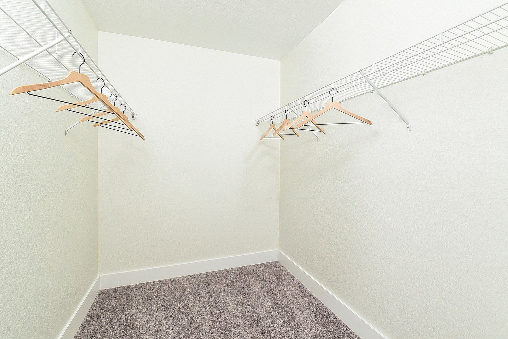 Spacious walk-in closet with neatly arranged wooden hangers and ample shelving space, perfect for organized living.
