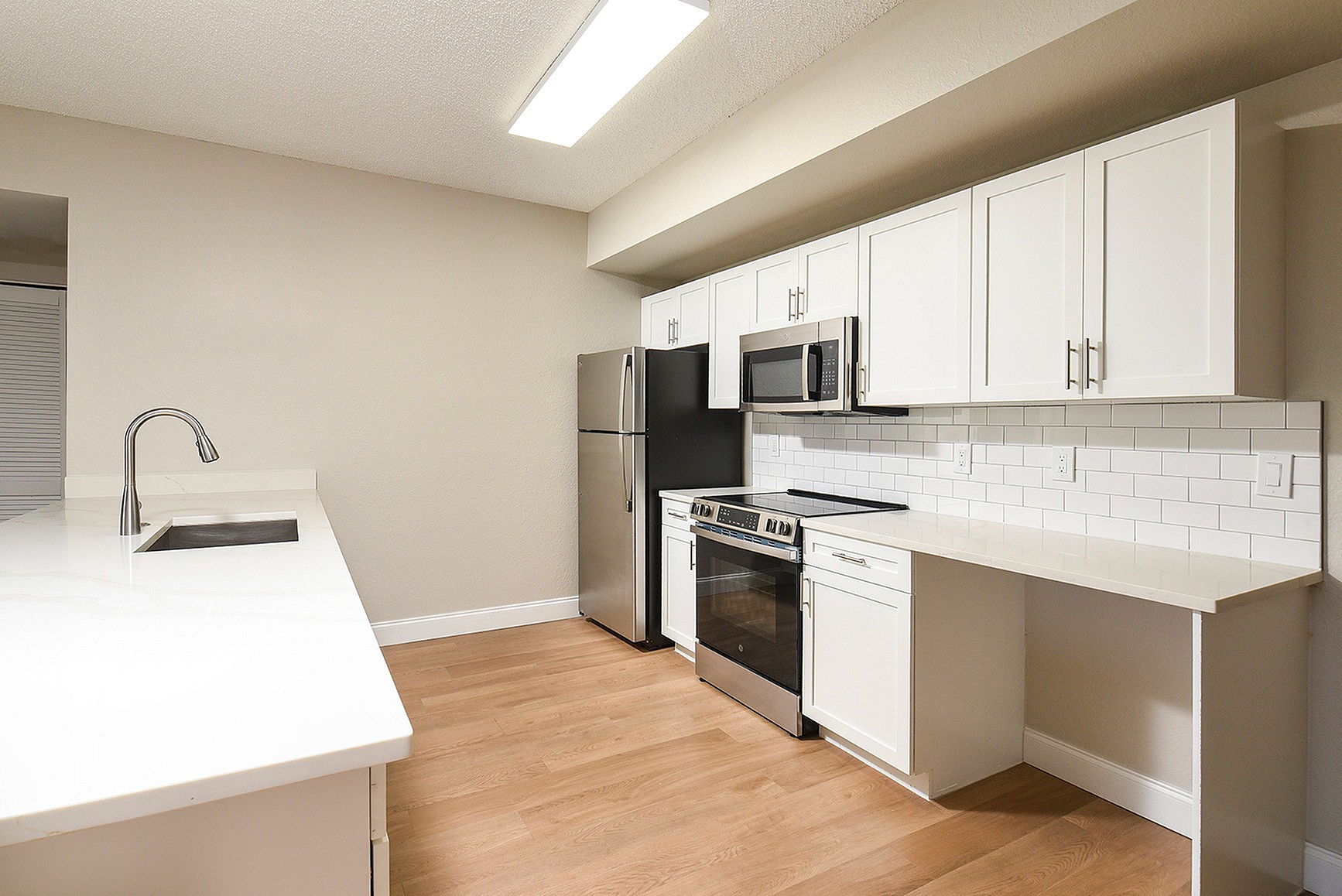Modern kitchen with sleek stainless steel appliances, white cabinetry, and elegant subway tile backsplash.