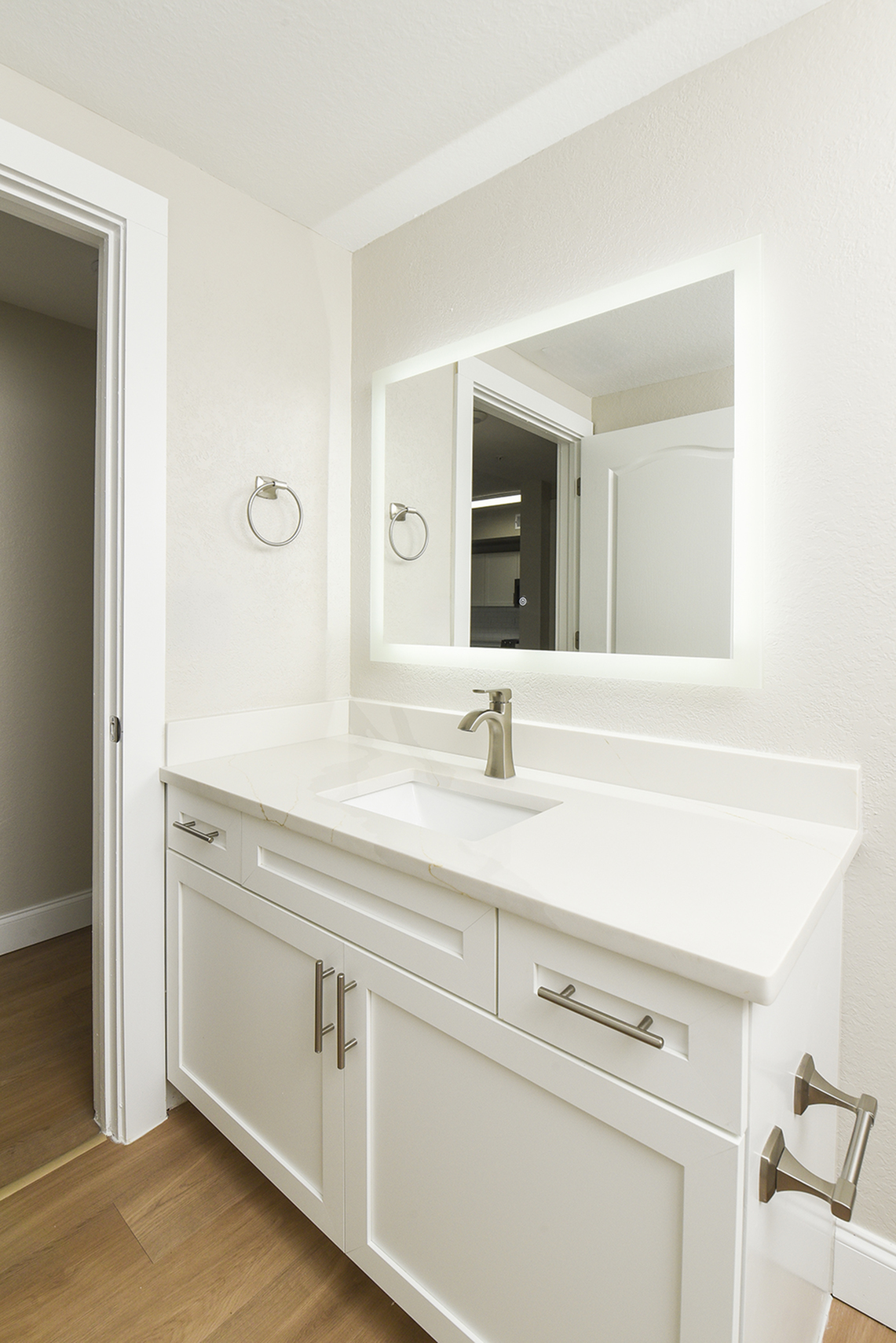 Chic bathroom vanity with a sleek white countertop, modern brushed metal fixtures, and an illuminated mirror.