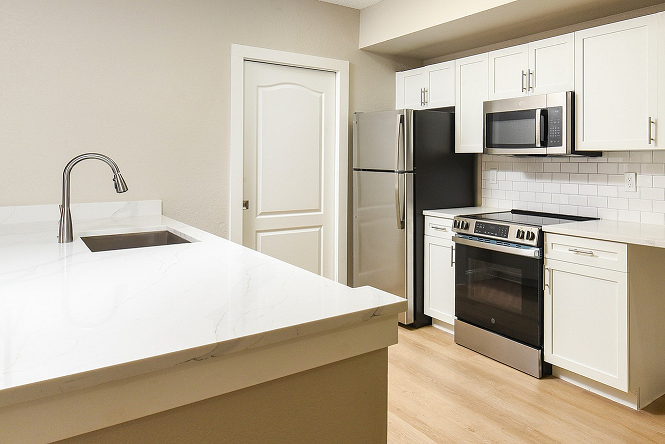 Modern kitchen with sleek stainless steel appliances, elegant white cabinetry, and a spacious marble countertop island.