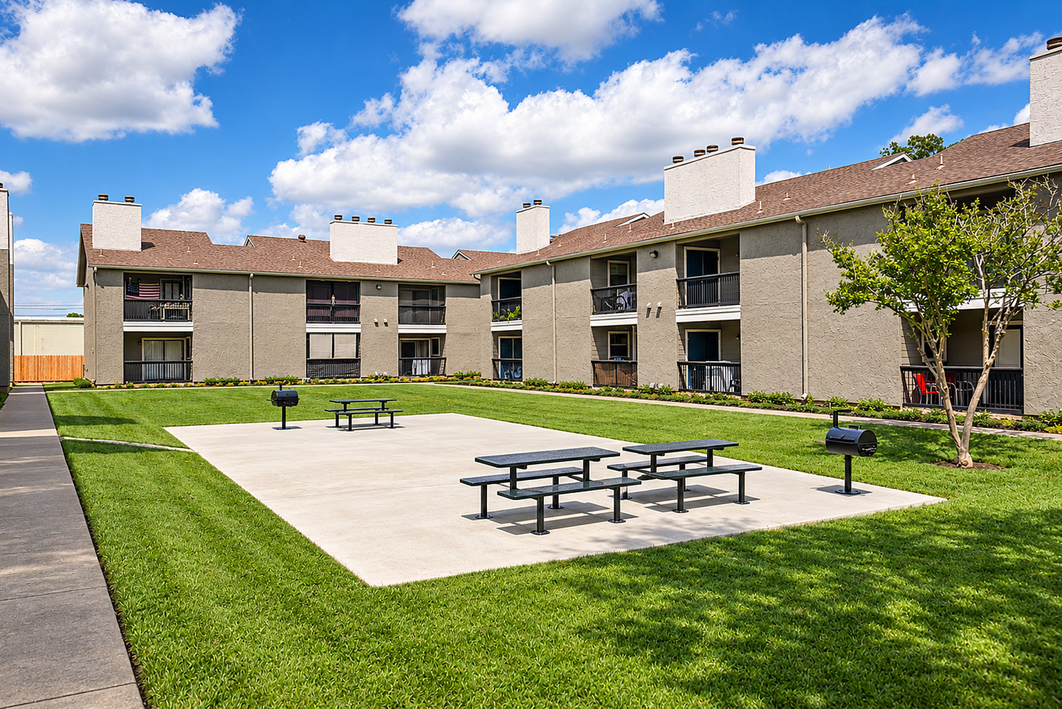 Charming apartment complex with spacious balconies overlooking a manicured lawn and inviting outdoor picnic area.