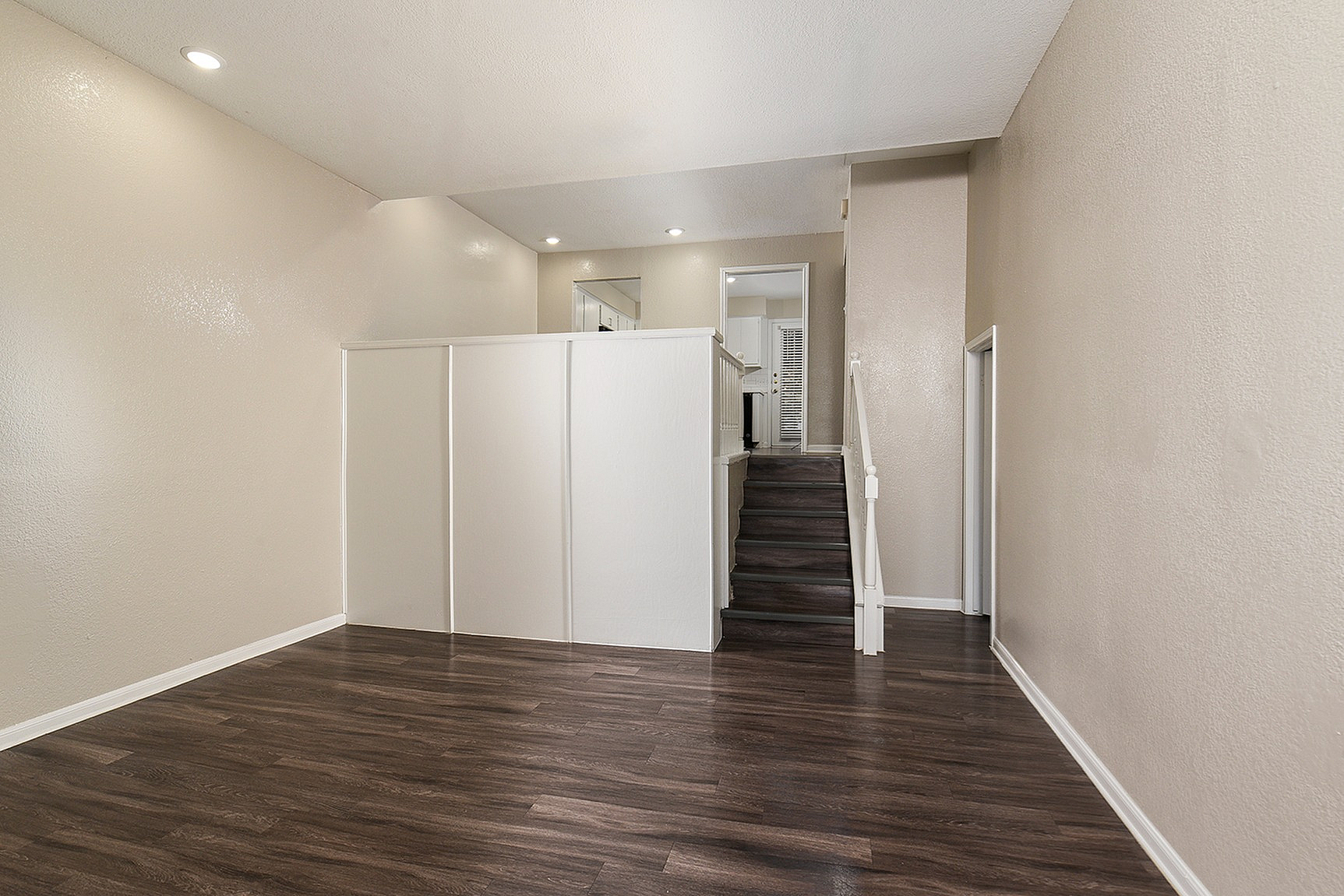 Stylish split-level apartment featuring sleek wooden flooring, abundant natural light, and a contemporary open staircase leading to a cozy kitchen area.