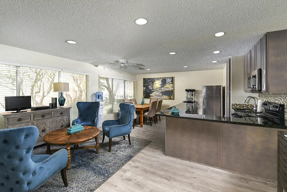 Leasing office with blue chairs, large table, and open kitchen