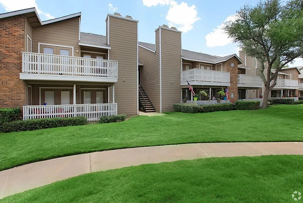 Inviting two-story apartment complex with balconies and lush green landscaping on a sunny day.