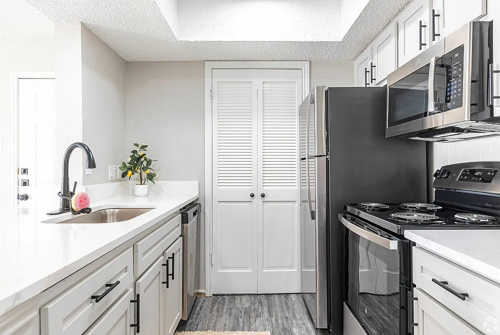 Modern kitchen with sleek white cabinetry, stainless steel appliances, and elegant countertops.