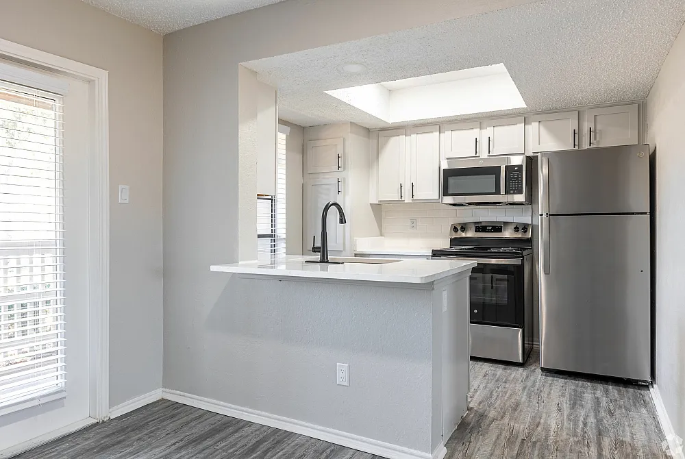 Modern kitchen with stainless steel appliances and sleek white cabinets.