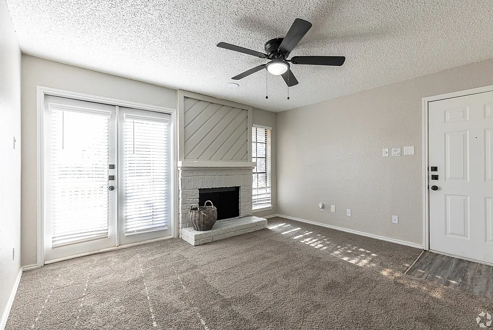 Inviting living room featuring a white brick fireplace, ceiling fan, and natural light through patio doors.
