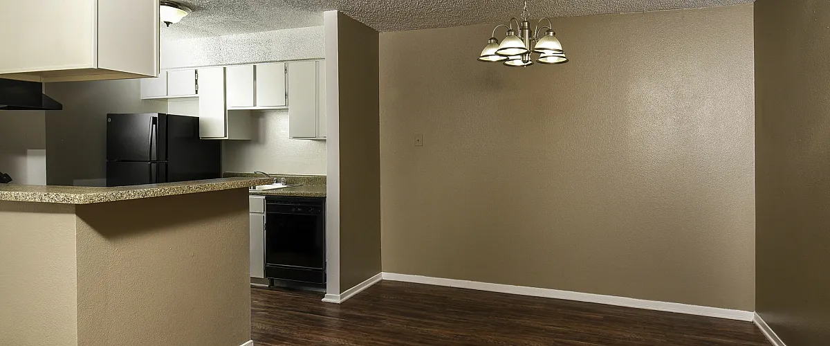 Kitchen with white cabinetry and a warm dining area with plank flooring.