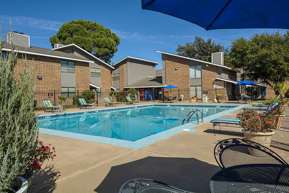 Inviting outdoor swimming pool surrounded by sun loungers and modern apartment buildings.