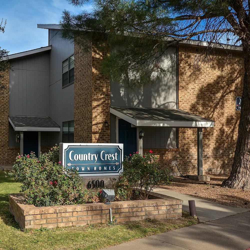 Charming exterior view of Country Crest Townhomes surrounded by lush greenery.