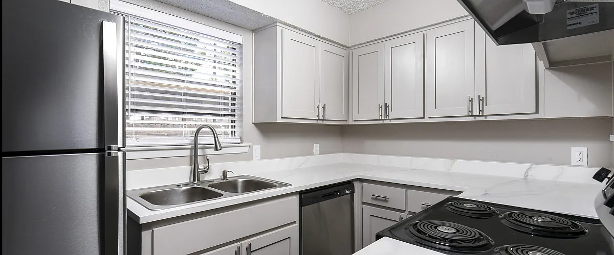Contemporary kitchen with stainless steel appliances, white cabinets, and marble countertops.