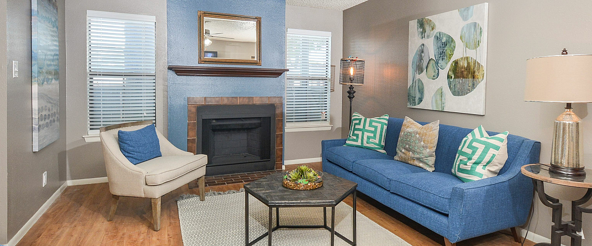 Inviting living room with a blue accented sofa, armchair, fireplace, and decorative pillows.