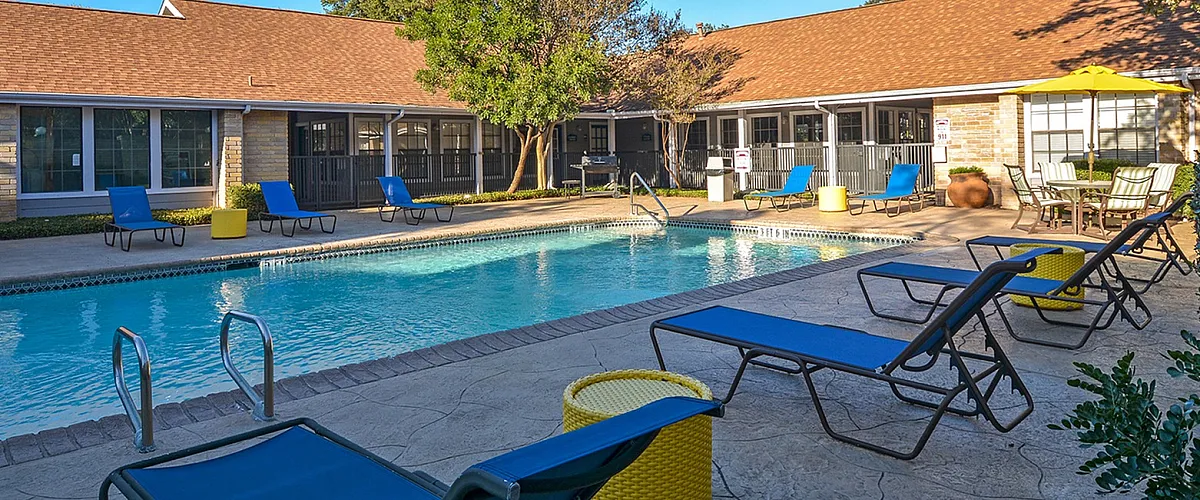 Inviting outdoor pool area with lounge chairs and vibrant decor under a clear blue sky, perfect for relaxation.