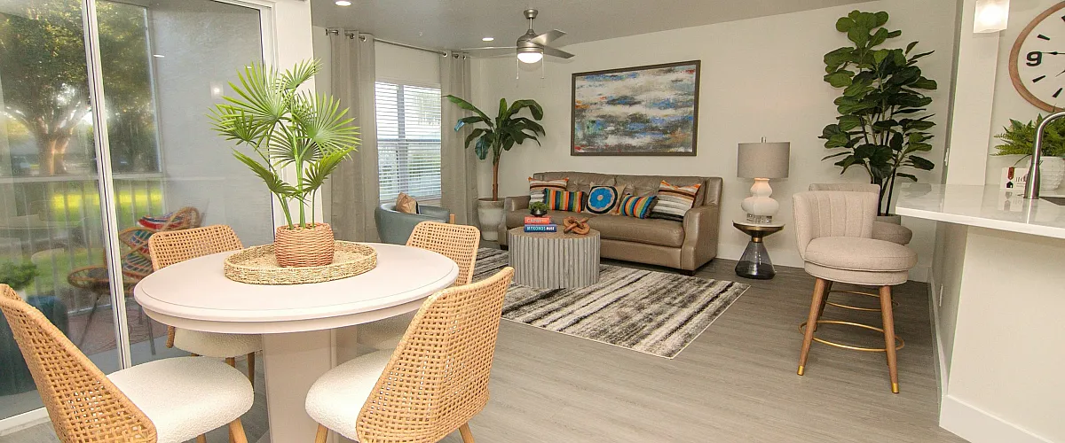 Bright, open-concept living area featuring modern decor, stylish dining set, and cozy living space with lush greenery.