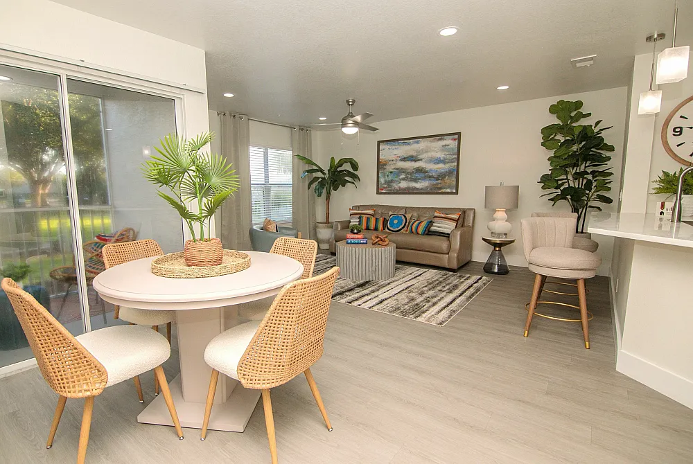 Contemporary open-plan living space with elegant dining area, cozy sofa under modern art, and lush greenery accents.
