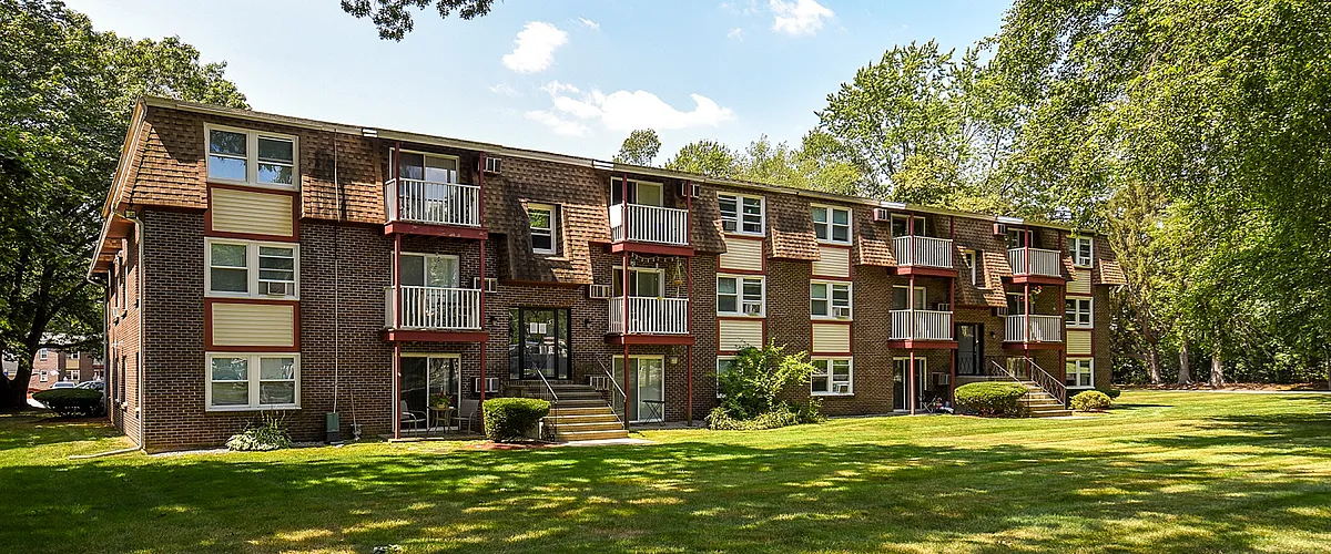 Charming apartment building with private balconies and lush green surroundings, perfect for tranquil living.