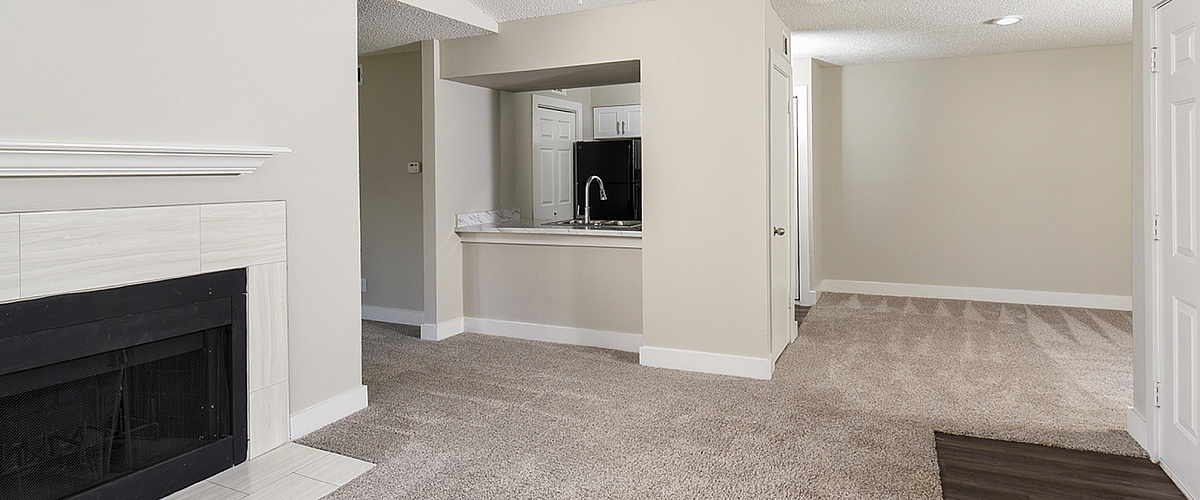 Modern apartment interior featuring a cozy living room with a sleek ceiling fan and elegant fireplace, open access to a contemporary kitchen.
