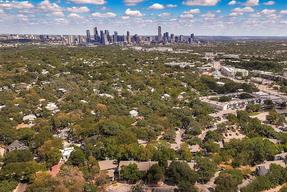 Stunning aerial view of Austin's cityscape surrounded by lush greenery, showcasing a harmonious blend of urban and natural beauty.