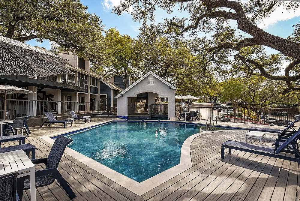 Inviting outdoor pool area with stylish lounge chairs and lush greenery, perfect for relaxation and leisure.