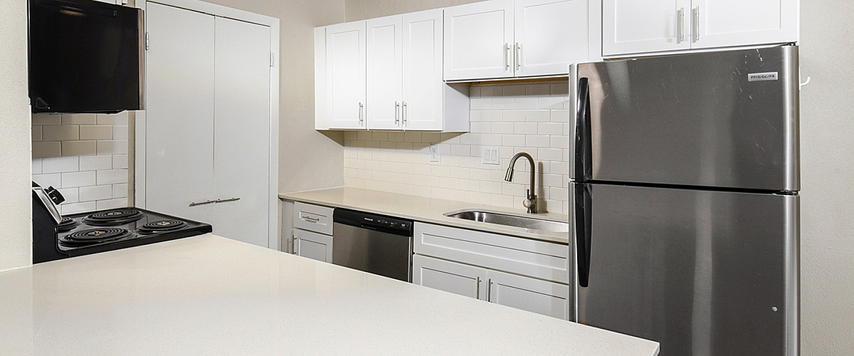 Modern kitchen with sleek stainless steel appliances, pristine white cabinetry, and elegant countertops.