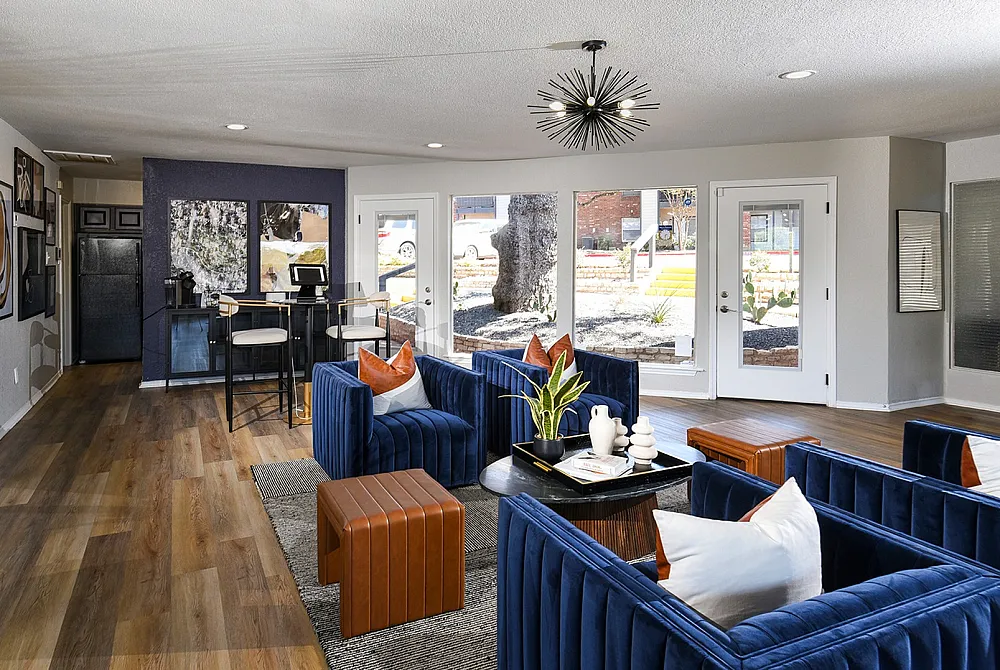 Contemporary living space with chic blue velvet seating, stylish lighting, and expansive windows offering a bright and inviting ambiance.