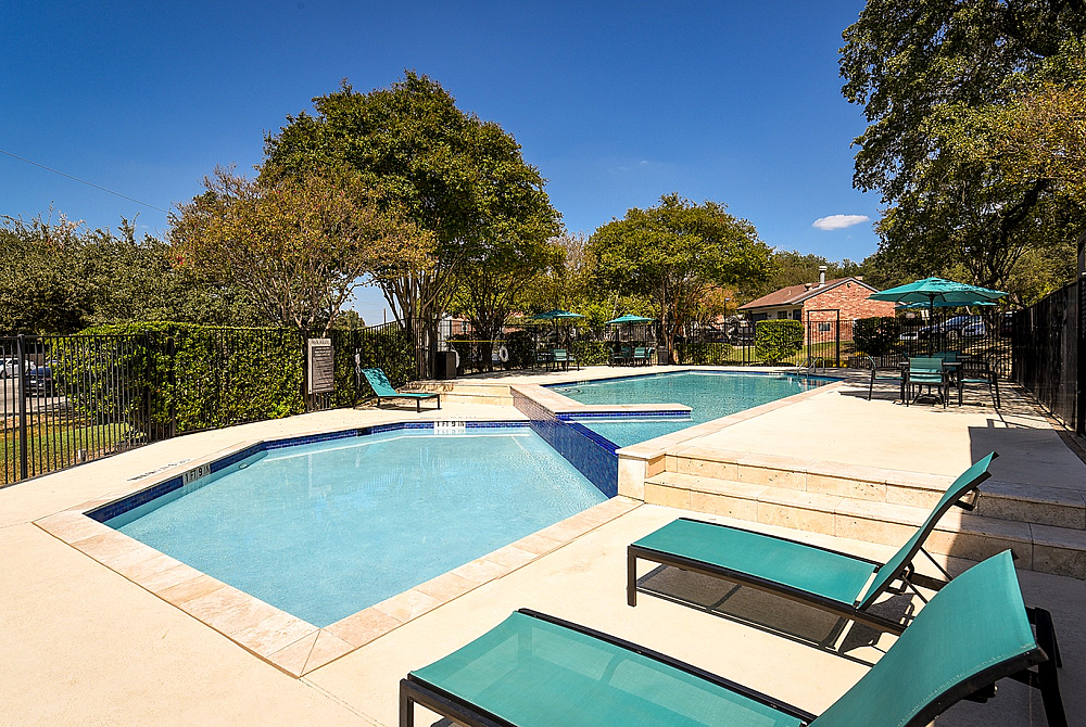 Inviting outdoor swimming pool surrounded by lush greenery and sun loungers, perfect for relaxation and leisure.