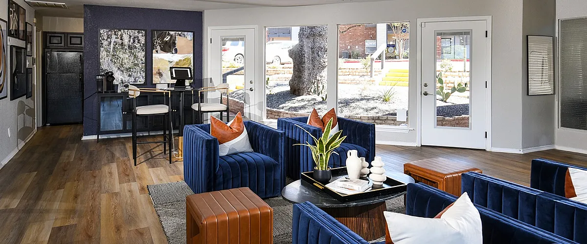 Modern living room with elegant blue velvet seating, natural wood flooring, and vibrant decor, offering a stylish and inviting atmosphere.