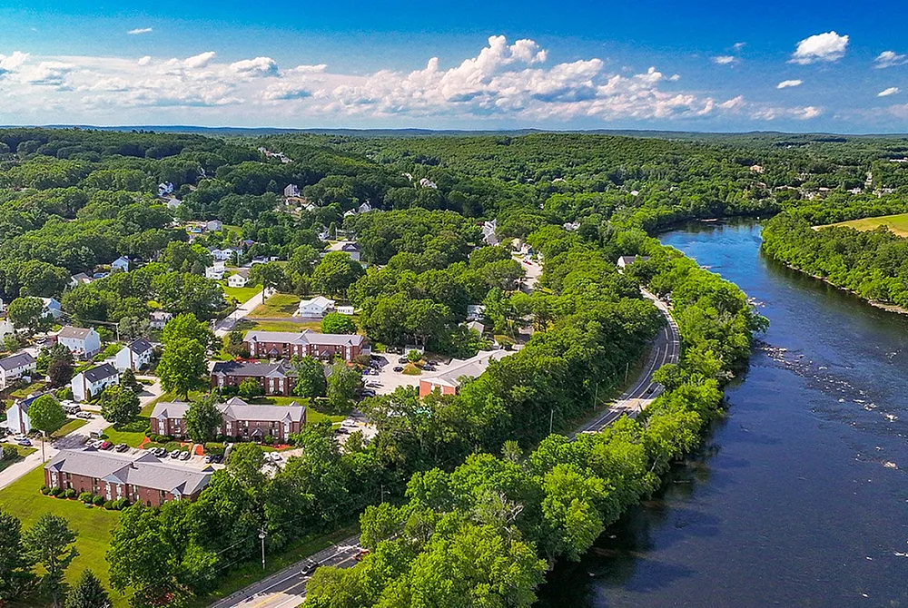 Stunning aerial view of a serene riverside neighborhood surrounded by lush greenery, offering a perfect blend of nature and suburban living.