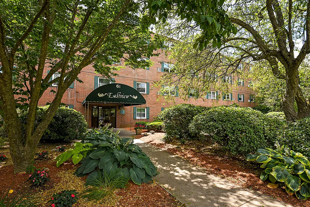 Charming brick apartment complex surrounded by lush greenery and a welcoming entrance at Eastview.