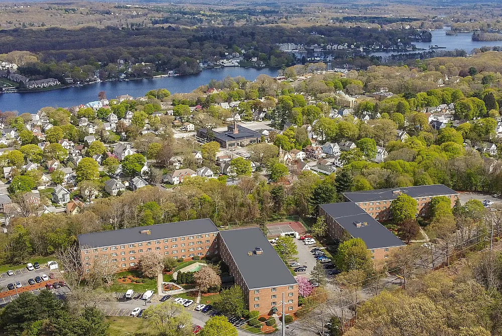 Beautiful aerial view of a serene neighborhood with lush greenery and picturesque lake, showcasing attractive residential buildings.