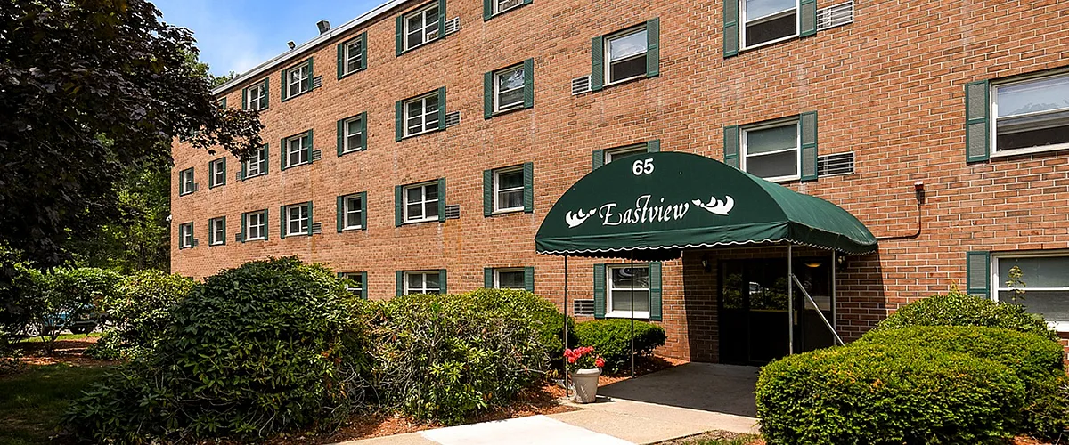 Charming brick apartment complex surrounded by lush greenery and picturesque landscaping.